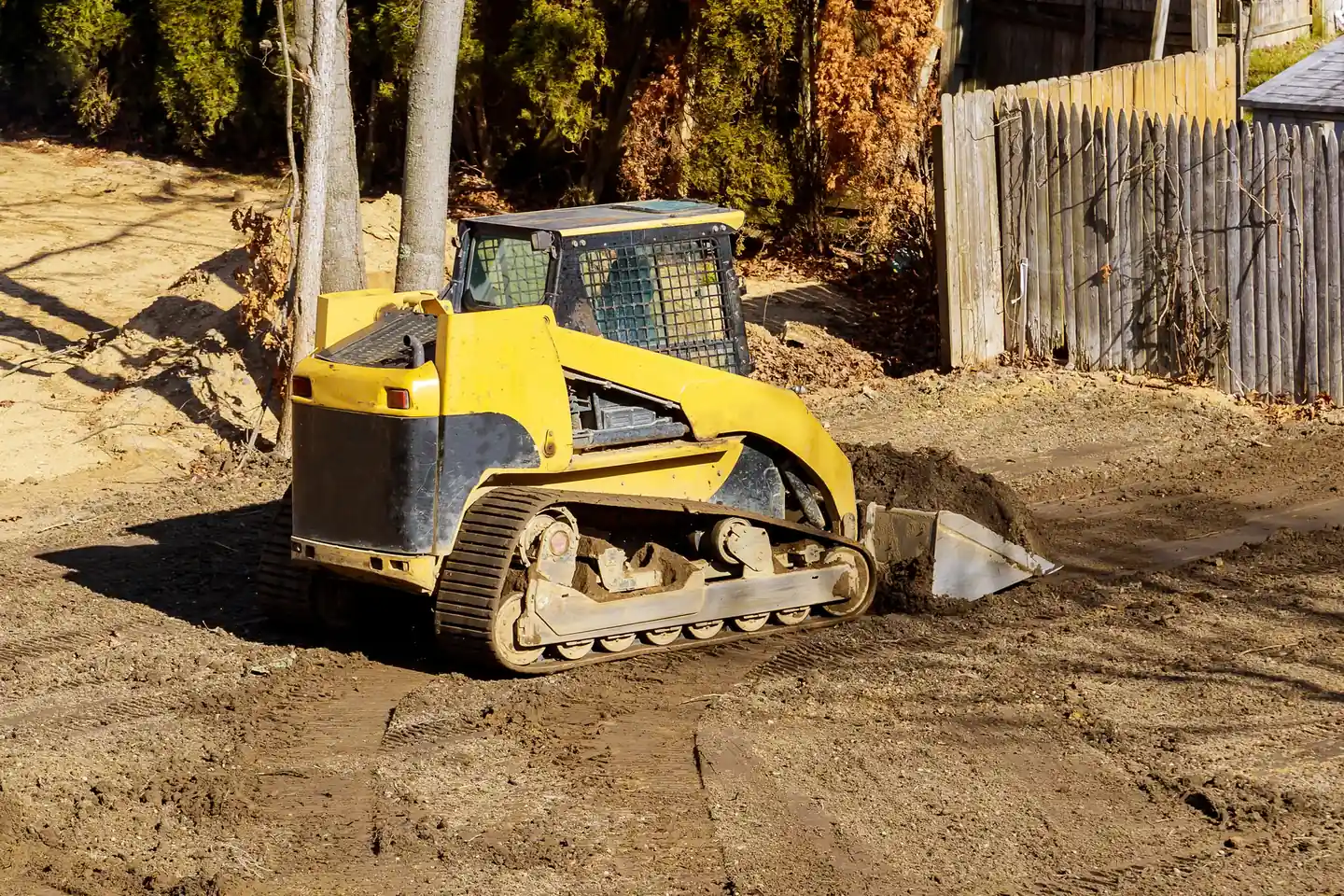 Compact track loader regrading a backyard so water drains away from the house