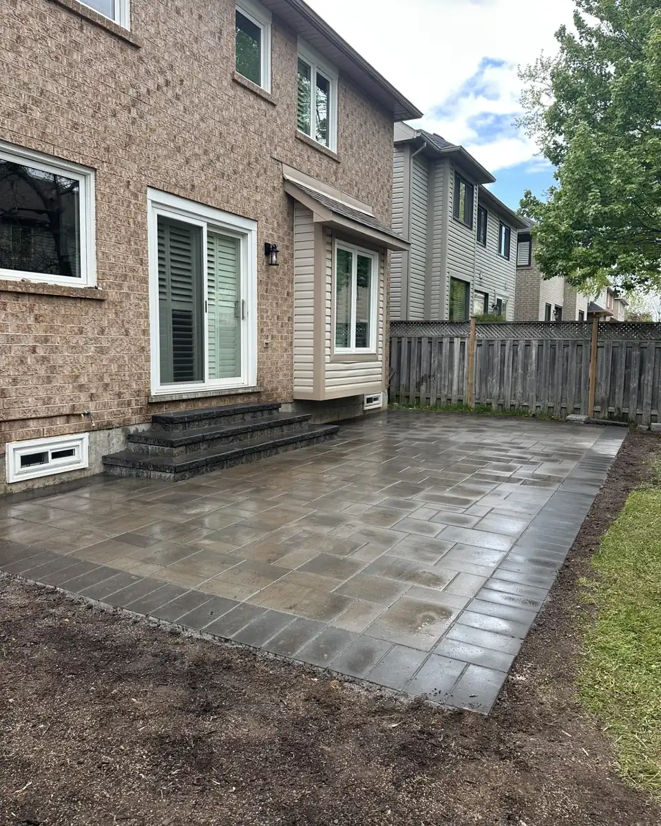 New interlock patio and steps behind a brick house