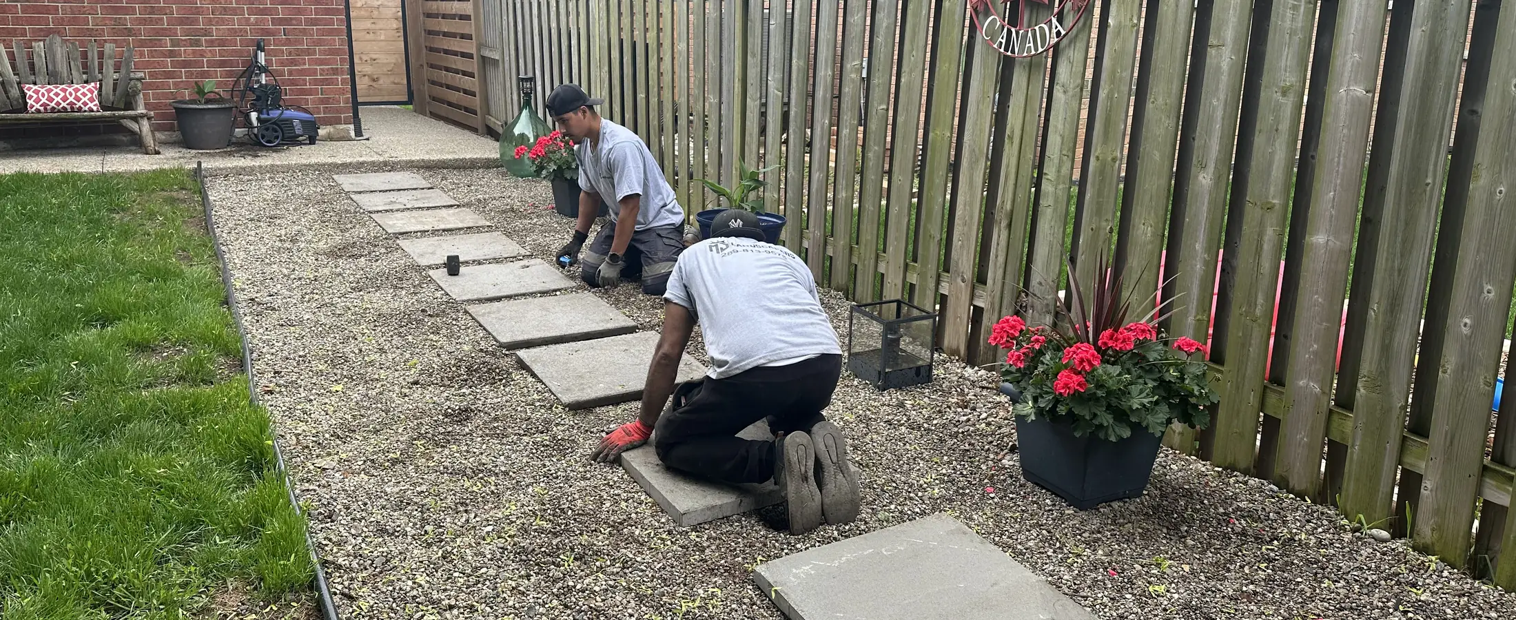 Crew members setting stepping stones along a side-yard fence