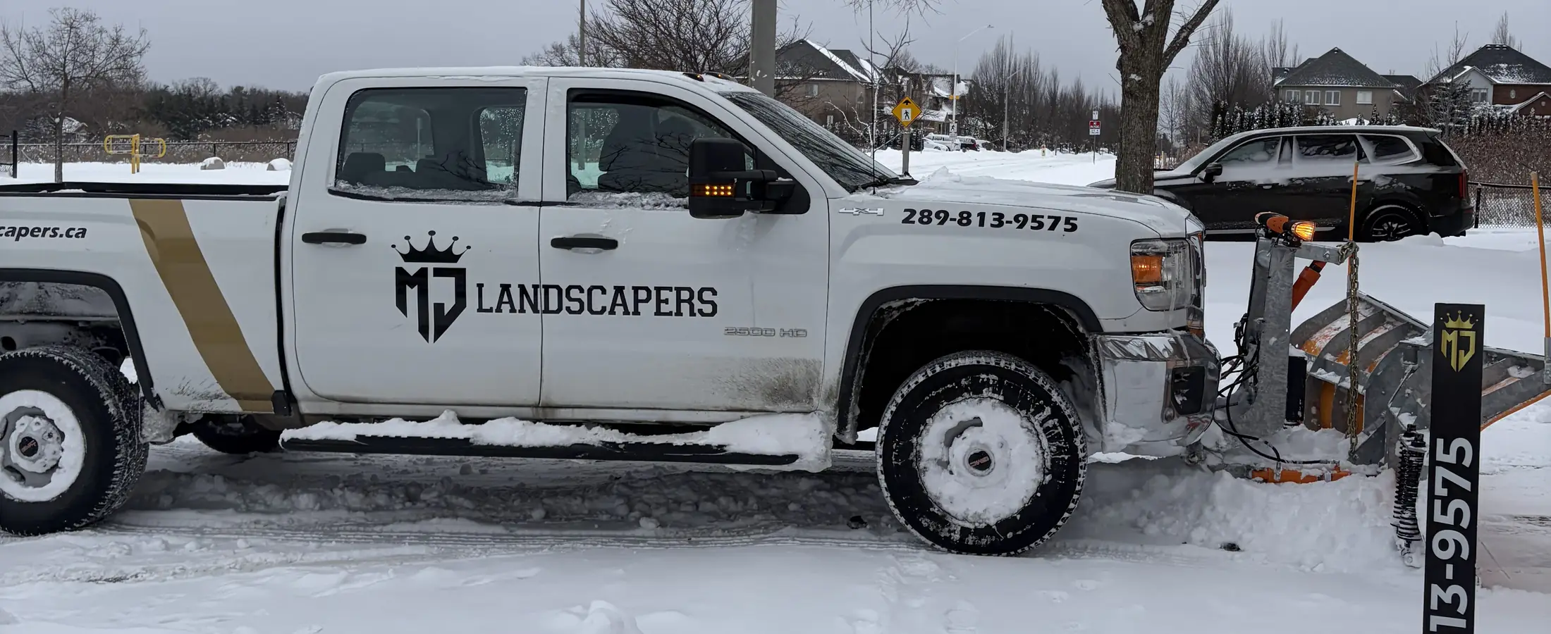 Branded MJ Landscapers plow truck on a snowy street