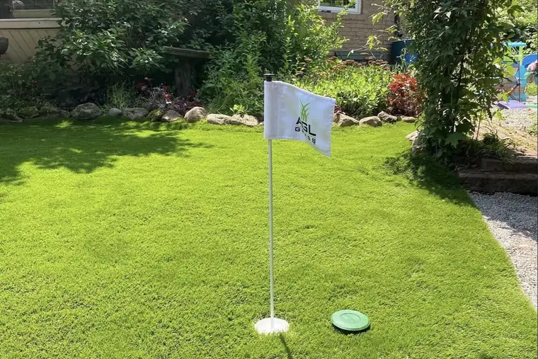 Backyard putting green with a flag beside a garden bed