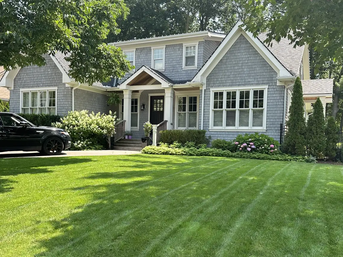 Freshly striped front lawn in front of a grey shingle house